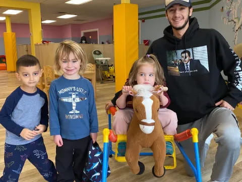 a person and kids posing with a stuffed animal