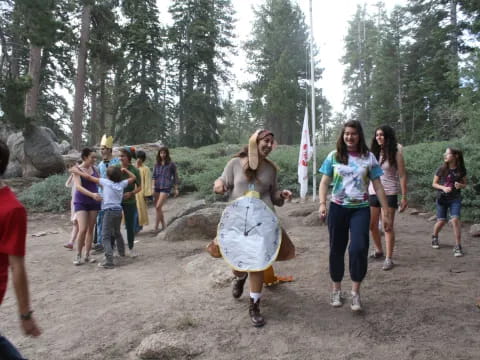 a group of people walking on a dirt path with trees and rocks