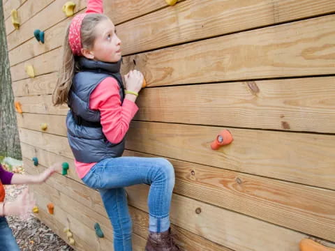 a girl climbing a wooden wall