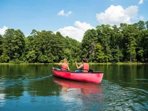 a couple of people in a red canoe on a lake with trees