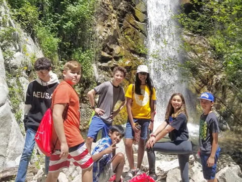 a group of people posing for a photo next to a waterfall