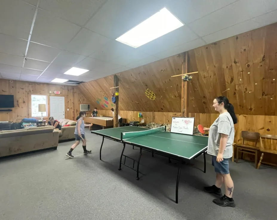 a man and a boy playing ping pong in a room with a wood wall and a wood