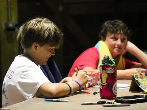 a couple of boys sitting at a table with a can of soda