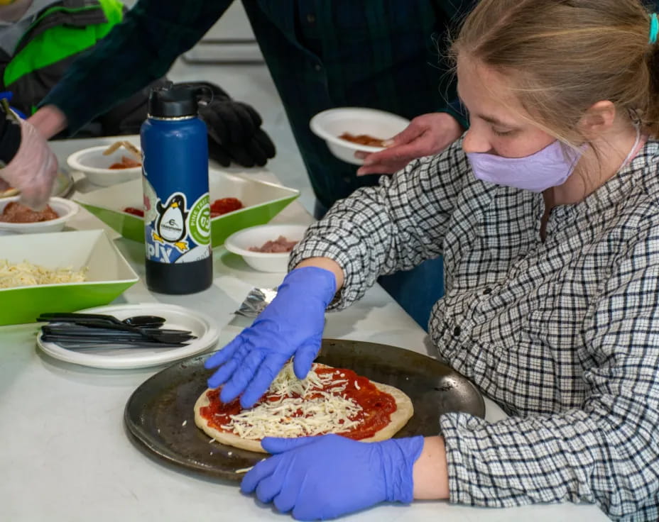 a person in a surgical scrubs preparing a pizza