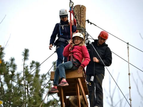 a group of people on a wooden structure with ropes and harnesses