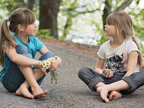 a couple of girls sitting on the ground and eating