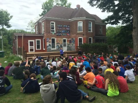 a group of people sitting on the grass in front of a building