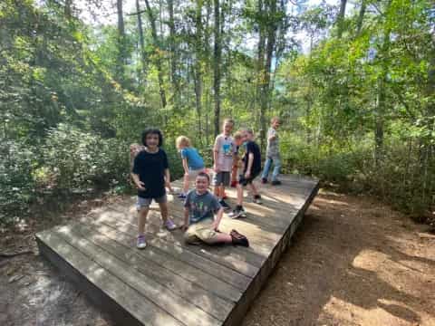 a group of people on a wooden bridge in the woods