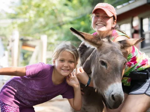a person and a girl petting a donkey