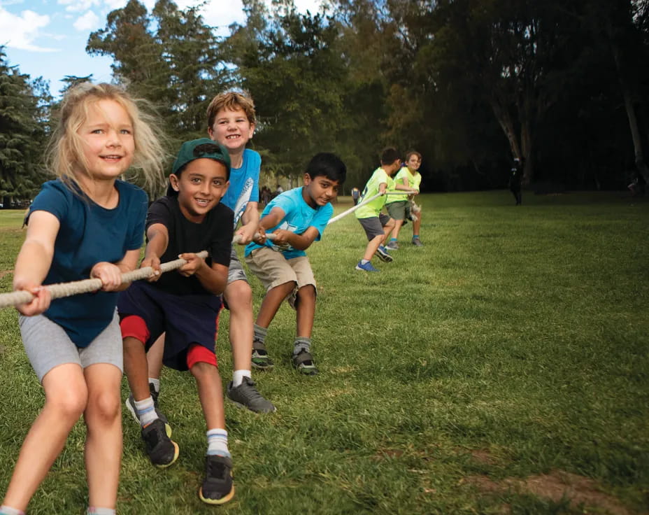 a group of kids running on a grass field