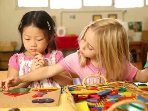 a couple of young girls playing with toys in a classroom