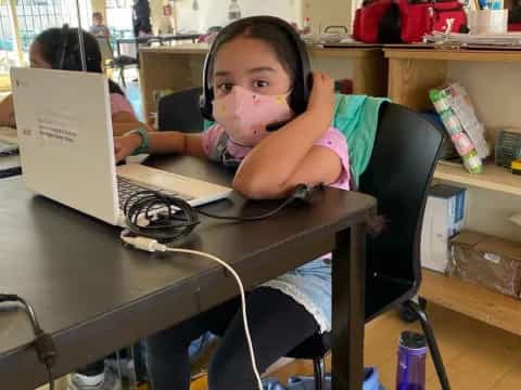 a girl sitting at a desk with a laptop