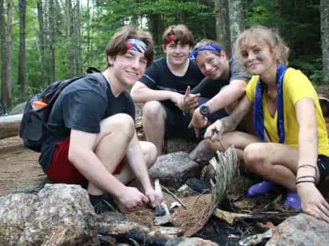 a group of people sitting on a log in the woods