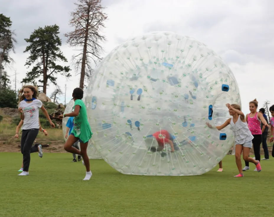 a group of people running around a large bubble