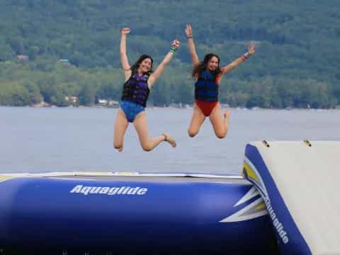 two girls jumping off a boat