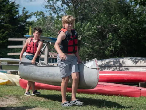 a couple of boys standing next to a boat