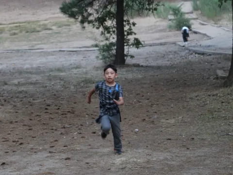 a boy standing in a dirt field