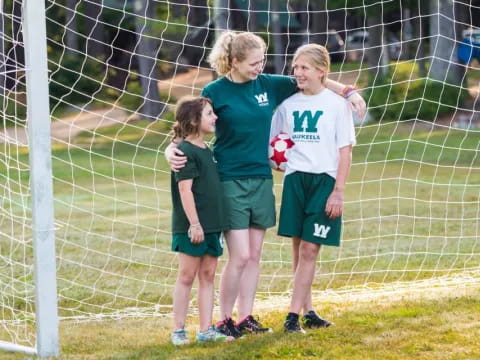 a group of girls standing in front of a football goal