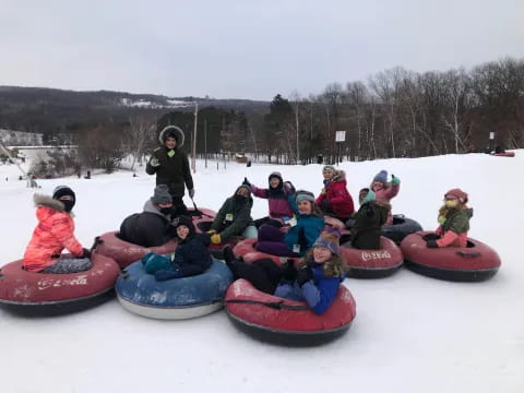 a group of people sitting on pink and black sleds in the snow