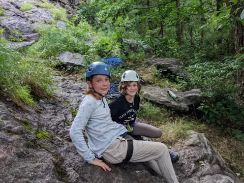 two people wearing helmets and sitting on a rock