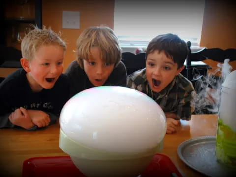 a group of boys sitting at a table with a large white egg