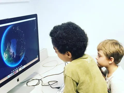 a couple of boys looking at a computer screen