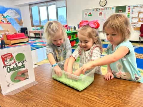 a group of children sitting at a table with a cake