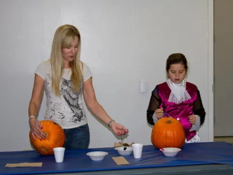 a woman and a girl carving pumpkins