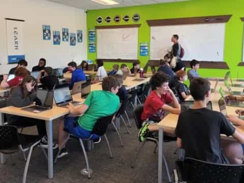 a group of people sitting at tables with laptops