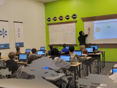 a classroom with people sitting at desks and a projection screen