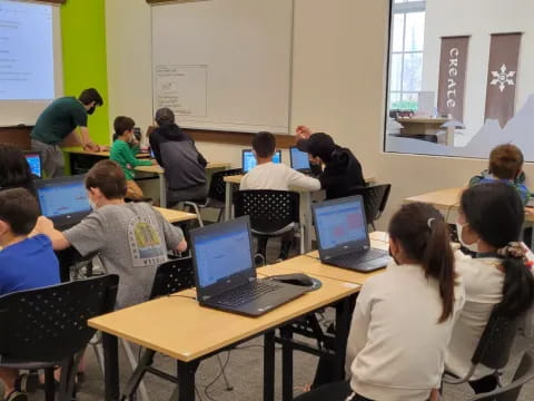 a group of people sitting at tables with laptops