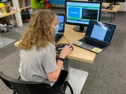 a person sitting at a desk using a laptop computer