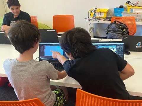 a group of people sitting at a table with laptops