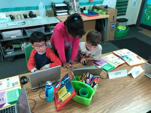 a person and two boys working on a laptop