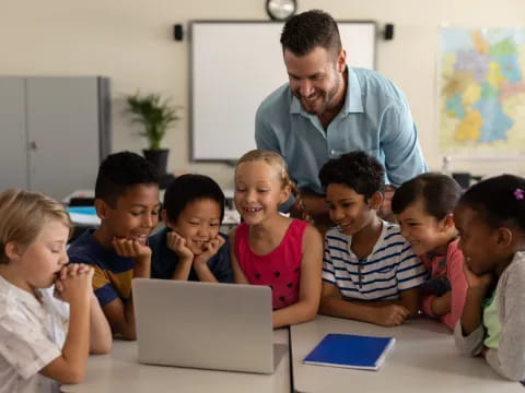 a man and a group of children looking at a laptop