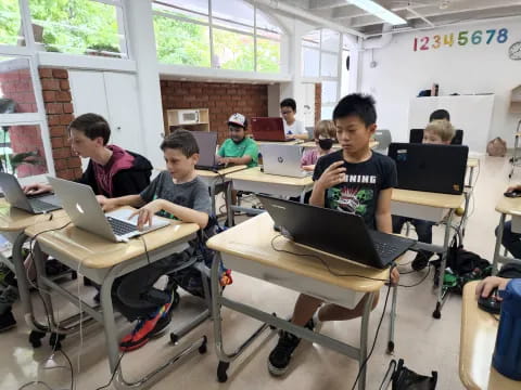 a group of people sitting at desks with laptops