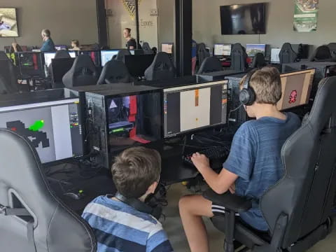 a couple of boys sitting in chairs with computers in front of them