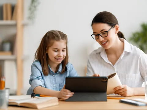 a person and a girl looking at a laptop