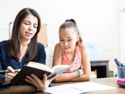 a woman and a girl looking at a book