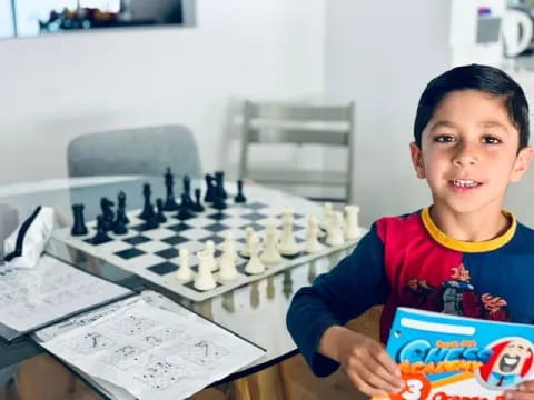 a boy sitting at a table with a board game and a board