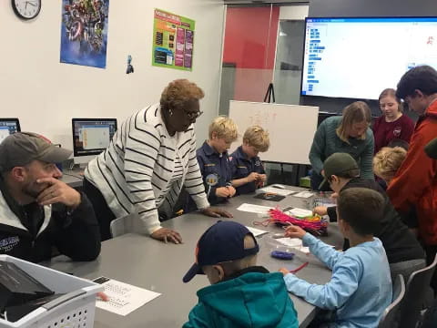 a group of people sitting at desks looking at a screen