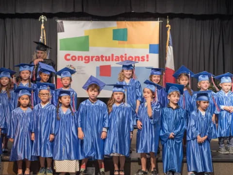 a group of children in blue graduation gowns and caps