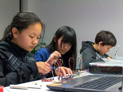 a group of kids working on a laptop