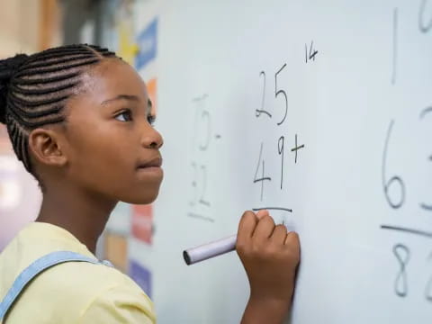 a young boy writing on a whiteboard