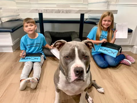 a dog and a couple of children sitting on the floor