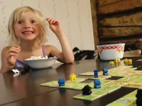 a girl sitting at a table with a bowl of cereal and a bowl of cereal