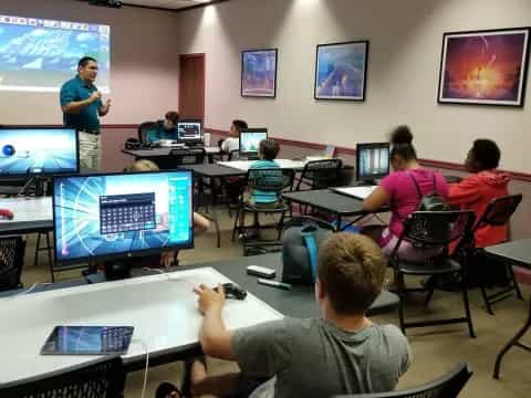 a group of people sitting at a table with computers