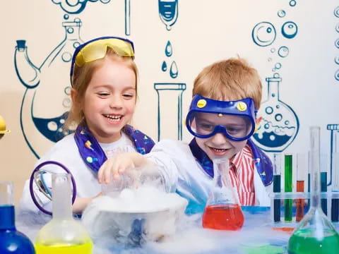 a couple of kids wearing goggles and holding a glass of liquid