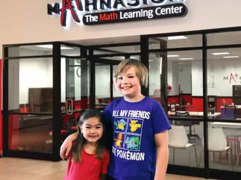 a boy and girl posing for a picture in front of a store