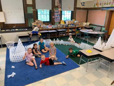 a group of people sitting on the floor in a room with tables and chairs